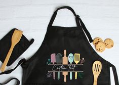 a black apron with utensils and cookies on the side that says create it