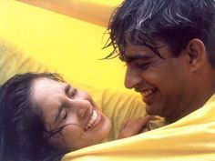 a man and woman laying in bed smiling at each other with wet hair on their heads