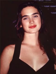 a close up of a person wearing a black dress and smiling at the camera with her eyes closed