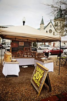 an outdoor food stand with a sign for jane joy bread on the table and other items under it