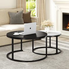 two tables sitting in front of a fire place with a laptop on one side and a coffee table on the other