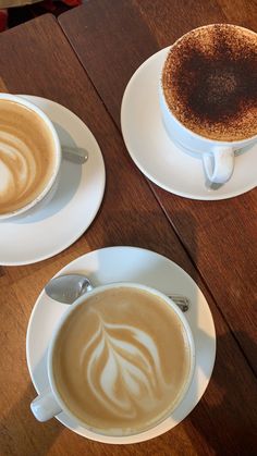 two cups of cappuccino on saucers with spoons