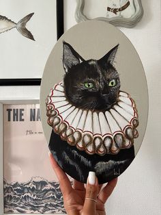 a black cat with green eyes is wearing a white dress and holding up a fan