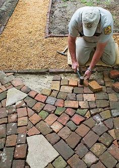 a man working on a brick walkway with a hammer in his hand and bricks laid around him