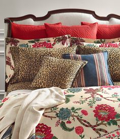 a leopard print comforter and pillows on a bed with red trim around the headboard