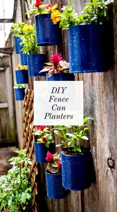 a wooden fence with blue planters filled with flowers and plants hanging from it's sides