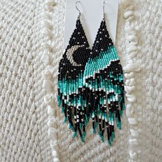 the earrings are made with seed beads and black, white, and green colors on them