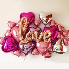 the balloons are shaped like hearts and have the word love spelled with them in gold letters