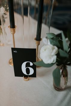 a table with candles and flowers in vases on the table number six is placed next to each other