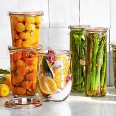 several jars filled with different types of vegetables and fruits next to each other on a counter