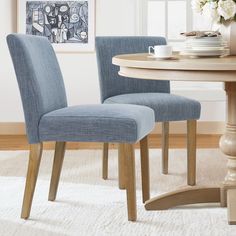 two blue chairs sitting on top of a white rug next to a wooden dining table