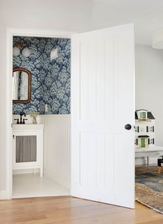 an open door leading to a bathroom with blue and white wallpaper