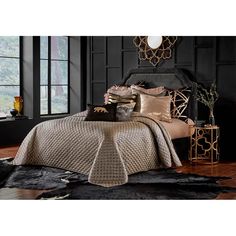 a bedroom with black walls and gold accents on the bed, along with decorative pillows