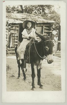 an old black and white photo of a child on a donkey