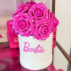 pink roses in a white box with the word barbie on it sitting on a table