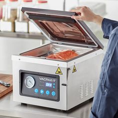 a person standing in front of a machine that has some meat on it and is holding the lid open