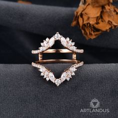 a diamond ring on top of a black cloth next to a dried flower and brown leaves