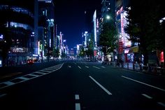 an empty city street at night with tall buildings