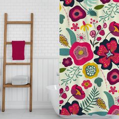 a shower curtain with colorful flowers on it next to a white bath tub and wooden ladder