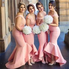 bridesmaids in pink dresses posing for the camera with white flowers on their bouquets