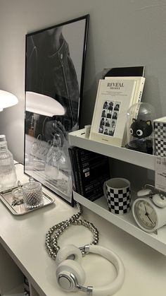 a white desk topped with books and headphones on top of it next to a lamp