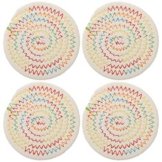 four white coasters with multicolored designs on them