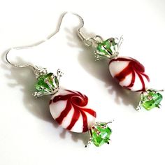 two candy canes are hanging from silver earwires with green crystal beads on them