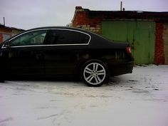 a black car parked in front of a brick building on a snow covered parking lot