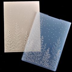 two frosted christmas cards on a black background with white snowflakes and trees