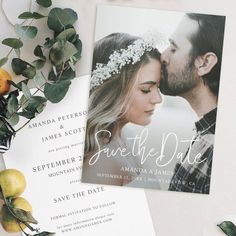 the wedding stationery is laid out next to some lemons and greenery, including an orange