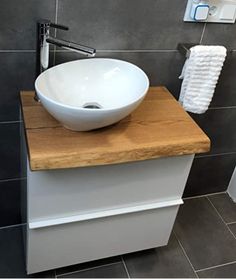 a white bowl sink sitting on top of a wooden counter