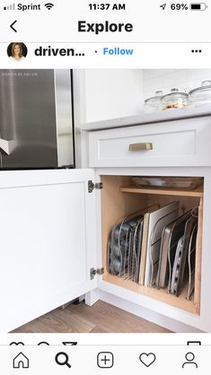 an open drawer in a kitchen filled with plates and pans on top of wooden flooring