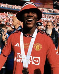 a man wearing a hat and holding a medal in front of a stadium full of people