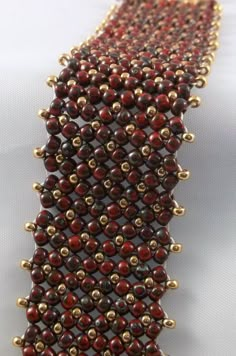 a red and gold beaded bracelet on a white surface with two rows of beads