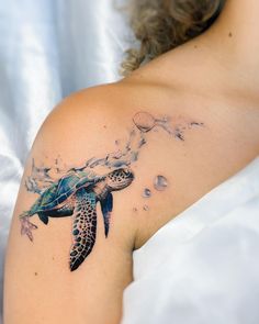 a woman with a tattoo on her shoulder has a sea turtle swimming in the ocean