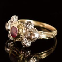 This amazing ring hails from the Georgian era of jewelry (c. 1715-1800). At its center lies a beautiful, rose-red ruby fashioned into a table cut, one of the oldest known gemstone faceting patterns. Flanking the ruby’s decoratively textured 22k yellow gold bezel, six exquisite rose-cut diamonds sparkle mysteriously from within their closed-back silver settings. The ring is crafted of sterling silver and 14k yellow gold, with a 22k yellow gold setting around the central stone. The table-cut ruby Antique Ruby Ring With Single Cut Diamonds, Victorian Ruby Ring With Center Stone, Antique Red Diamond Ring With Rose Cut Diamonds, Antique Ruby Rings With Single Cut Diamonds, Victorian Ruby Ring With Single Cut Diamonds, Victorian Ruby Ring With Rose Cut Diamonds, Antique Ruby Diamond Ring Hallmarked, Antique Ruby Ring With Rose Cut Diamonds, Antique Ruby Ring With Rose Cut Diamonds For Anniversary