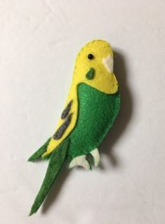 a small green and yellow bird sitting on top of a white table