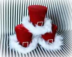 three red and white santa hats sitting next to each other on top of a striped surface