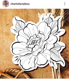 a white flower on top of a wooden table next to some wheat stalks and twine