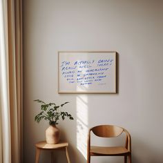 there is a chair and a potted plant in front of the wall with writing on it