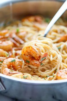 a fork full of pasta with shrimp and parmesan cheese on it in a pan