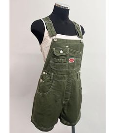 Short overalls with a multi pocket bib and logo patch detail. Traditional straps with clasp closures. Pockets on the front and back with button closures at the sides. Looks great paired with crop tops. SMALL: Waist: 26" | Hips: 40" | Inseam: 3.5" MEDIUM: Waist: 28" | Hip: 42" | Inseam: 3.5" LARGE: Waist: 30" | Hip: 44" | Inseam: 3.75" Material | 100% Cotton (Non-Stretchy Canvas/Denim) Care Instructions | Machine Wash or Hand Wash Cold  Measurements | 30" or 76 cm Top to Bottom 3.5" or 9 cm Inseam [Measured on a size Small] Model is 5'8 and wearing a size Small SMALL CUSTOMER REVIEWS 1. I'm 5'4 about 120 pounds and I ordered a small in the navy. They fit perfectly! I would recommend getting the size you usually wear. The fabric and stitching feel high quality. 2. The overalls are just great Affordable Utility Shortalls With Side Pockets, Cheap Denim Shortalls, Short Bibs Denim Overalls, Cheap Vintage Overall Jeans, Bibs Overalls For Women Short, Cheap Retro Medium Wash Overalls, Cheap Black Overall Shortalls, Affordable Medium Wash Bib Front Shortalls, Affordable Women's Shortalls With Side Pockets