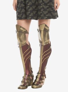 the legs and arms of a woman wearing knee high gladia boots with gold accents