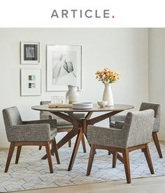 a dining room table with four chairs and a vase on the table in front of it