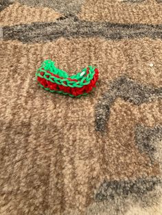 a red and green piece of string sitting on top of a carpeted floor next to a rug