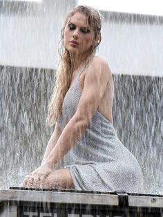 a woman sitting on top of a wooden box in the rain