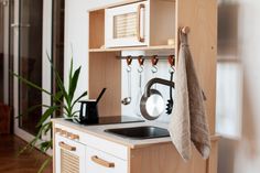 a kitchen area with sink, cabinets and pot holders on the wall next to a window