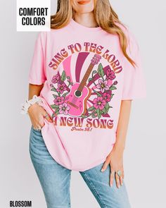 You will love our Comfort Colors Christian t shirt for women. It is based on the Bible verse Psalm 98:1. There is retro guitar and floral graphic on the front of this shirt.  This shirt would be great to wear to a Christian concert.  It is so trendy and cute and has a western flair. This is a great way to share your faith in Jesus with others. Comfort Colors T shirt Details: 100% ring-spun cotton Medium fabric (6.1 oz/yd² (206.8 g/m Relaxed fit Sewn-in twill label T shirt Care instructions: Mach Spring Band Merch T-shirt With Sublimation Print, Sublimation Print Band Merch T-shirt, Pink Relaxed Fit Band Merch T-shirt, Pink T-shirt With Screen Print For Concert, Pink Screen Print T-shirt For Concert, Pink Letter Print T-shirt For Concert, Spring Concert Crew Neck T-shirt, Pink Band Merch T-shirt For Concert, Pink Screen Print Top For Concert