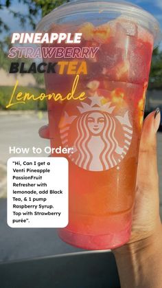 a person holding up a cup of tea in front of a window with the words pineapple strawberry black tea lemonade on it