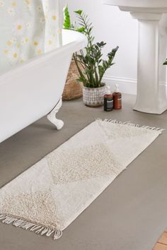 a white bath tub sitting next to a sink and a rug on the floor in front of it